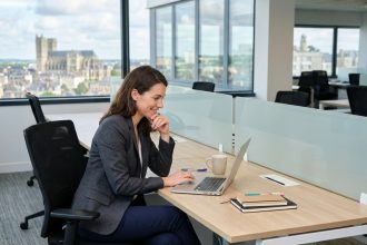 Femme en blazer au bureau avec vue sur Le Mans
